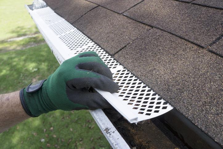 Contractor adjusting plastic gutter guards to get them to fit.